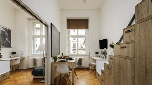 Une cuisine moderne avec un plancher en bois, des meubles blancs et un coin repas avec des chaises.