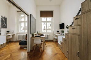Eine moderne Küche mit Holzboden, weißen Schränken und einem Essbereich mit Stühlen.