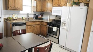 Une cuisine avec des meubles de rangement en bois, un réfrigérateur blanc, une cuisinière et un four à micro-ondes.