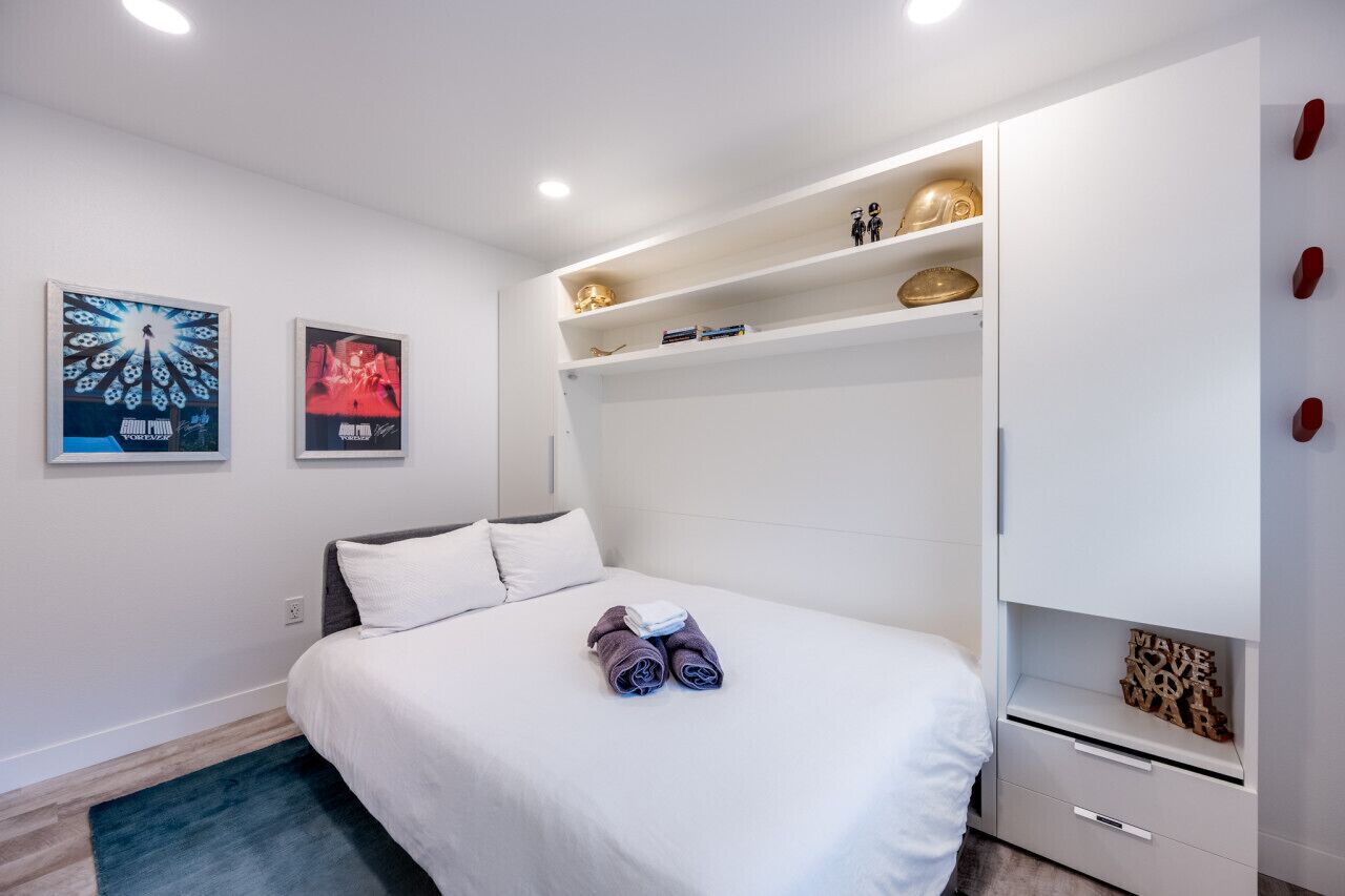 Un dormitorio moderno con cama, paredes blancas y armario empotrado.