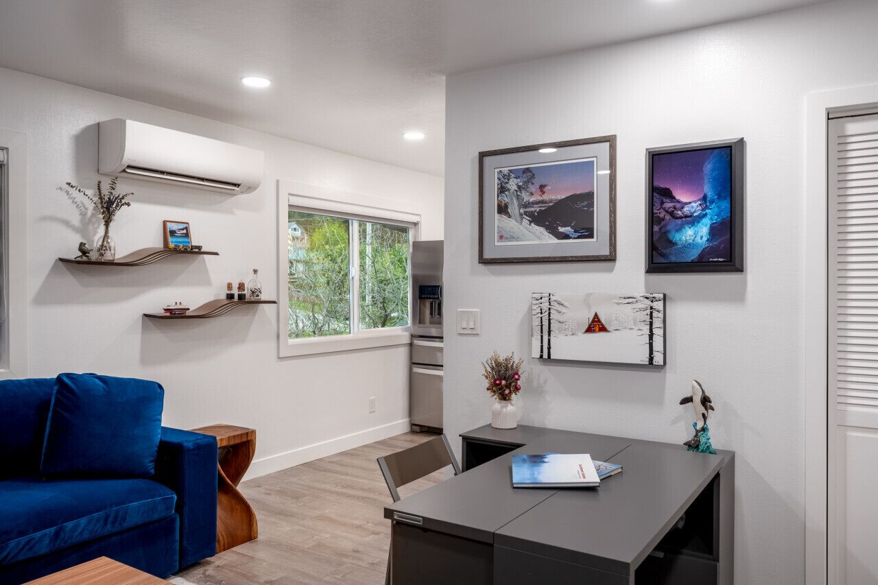 A modern living room with a blue sofa, a dining table, and artwork on the walls.