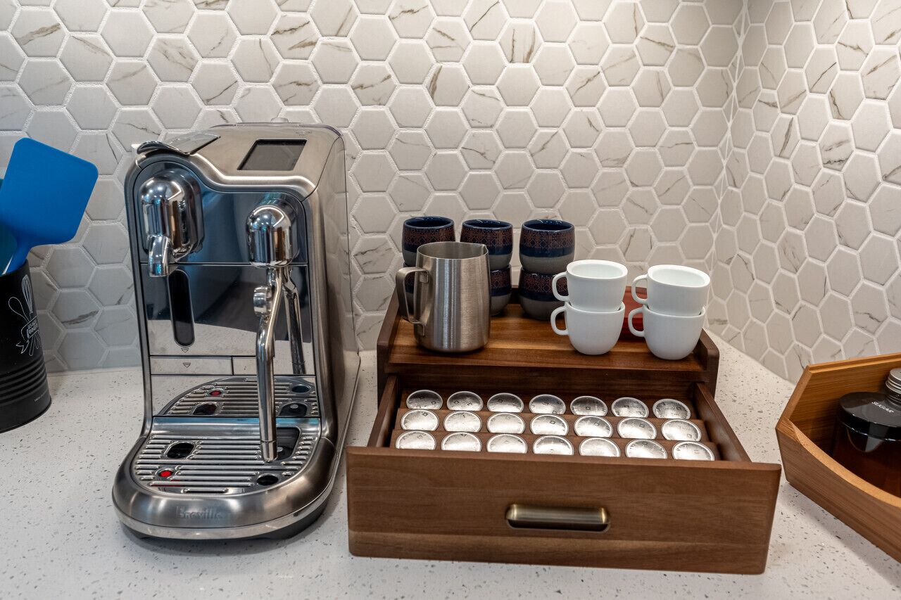 Une machine à café, un tiroir contenant des dosettes de café et un plateau avec des tasses et des mugs.