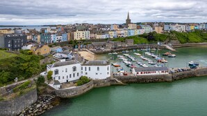 A coastal town with colorful buildings, a church spire, and a marina with boats. - Laston Garden Apartment - Tenby Harbour, Sea Views (Tenby)