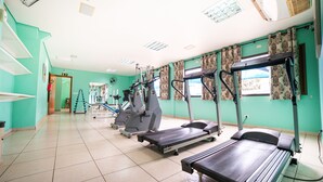 Een fitnessruimte met loopbanden, elliptische trainers en gewichten.