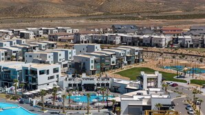 A modern residential area with multiple two-story buildings, a central swimming pool, and a landscaped park area.