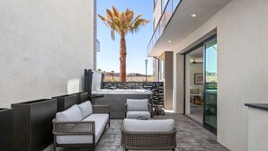 A modern outdoor seating area with wicker furniture, a central table, and a palm tree.