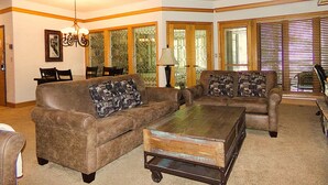 A living room with a brown sofa, a coffee table, and a dining area with chairs and a table. - Chateau DuMont Oversized 2 Bed 2 Ba CDMR (Keystone)
