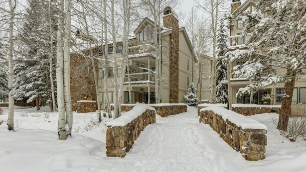 A snow-covered pathway leading to a multi-story building with stone walls and a balcony. - Chateau DuMont Oversized 2 Bed 2 Ba CDMR (Keystone)