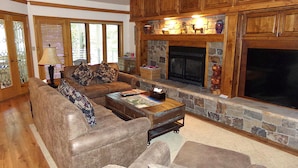 A living room with a stone fireplace, wooden cabinets, and a large flat-screen TV. - Chateau DuMont Oversized 2 Bed 2 Ba CDMR (Keystone)
