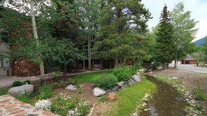 A landscaped garden with a stone pathway, a small stream, and various plants. - Chateau DuMont Oversized 2 Bed 2 Ba CDMR (Keystone)