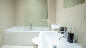 A modern bathroom with a glass-enclosed shower, a white toilet, and a sink with a mirror above it. - 3BR Waterfront Apt - 10 min to City Center Ipswich (Ipswich)