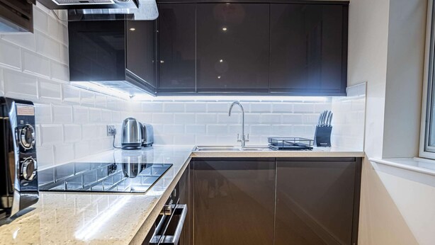 A compact kitchen with a built-in stove, a kettle, and a sink. - 3BR Waterfront Apt - 10 min to City Center Ipswich (Ipswich)