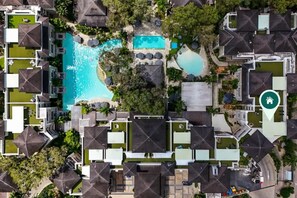 An aerial view of a resort with multiple swimming pools, a central pool, and a guesthouse icon indicating a location.