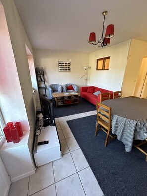 A compact living space with a sofa, a dining table, a TV, and a bookshelf. - Ground floor, balcony, tv, 50m², Villard de Lans (Villard-de-Lans)