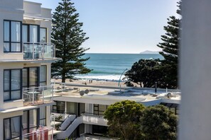 A multi-story building with balconies overlooking a beach and ocean.