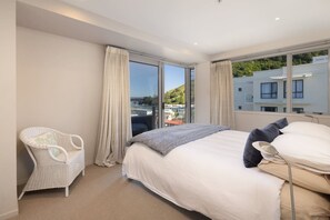 Habitación de hotel con cama, una silla y vista a un edificio y follaje.