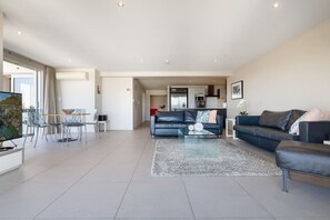 A modern living room with a sofa, a coffee table, and a dining area with chairs.