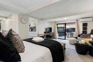 A hotel room with a bed, a desk, a television, and a view of the outside.