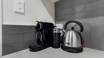 A kitchen counter with a coffee maker and a kettle.