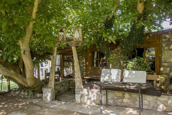 A rustic wooden cabin with stone walls, a wooden staircase, and a table with chairs.