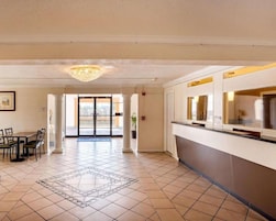 Un vestíbulo de hotel con zona de comedor, mostrador de recepción y suelo estampado.
