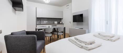 A modern hotel room with a bed, a desk, a chair, and a TV.