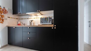 A modern kitchen with black cabinets, a microwave, and a wooden countertop. - Italianway - Cermenate 7 (Milan)