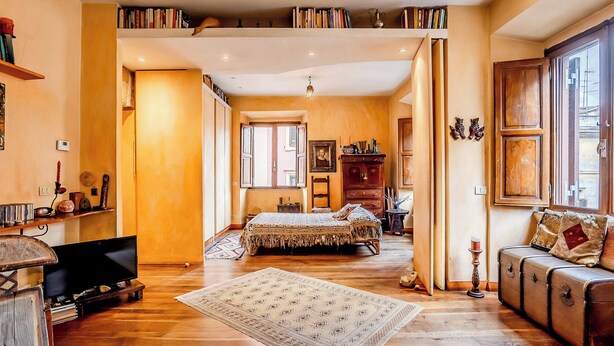 A spacious room with a large bed, a vintage sofa, and a television. There are bookshelves and a wooden cabinet. - Lovely 2-bed Apartment in Roma (Rome)