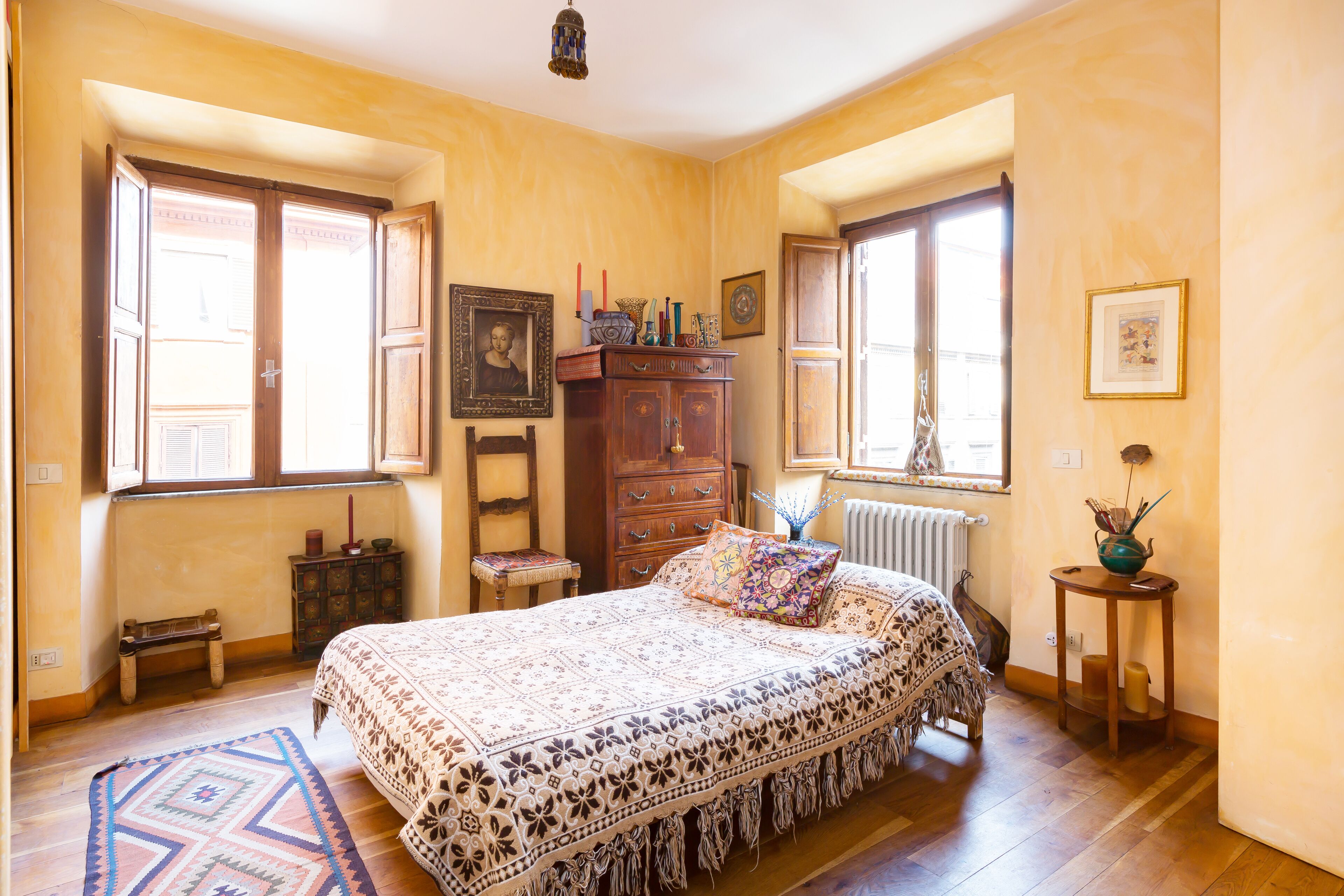 A bedroom with a large bed, wooden furniture, and a window with a view.