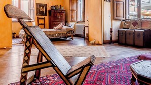 A cozy room with a bed, a wooden chair, a sofa, and a window with a view. - Lovely 2-bed Apartment in Roma (Rome)