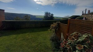 A well-maintained garden with a wooden fence, a grassy lawn, and a view of rolling hills in the distance. - Ferienwohnung Hansen, in Ruhiger Lage mit Wunderschönem Ausblick (Welschbillig)