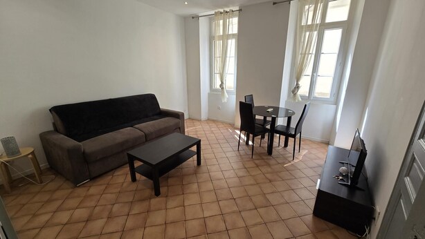 A living room with a sofa, a coffee table, and a dining area with chairs and a table. - Studio Climatisé Intra Muros Secteur Vernet Calme et Lumineux (Avignon)