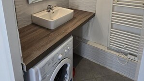 A compact bathroom with a sink, mirror, and a washing machine. - Studio Climatisé Intra Muros Secteur Vernet Calme et Lumineux (Avignon)