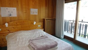 A wooden room with a bed, a radiator, and a window with a view.