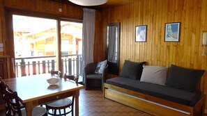 A wooden interior with a sofa, a dining table, and chairs.