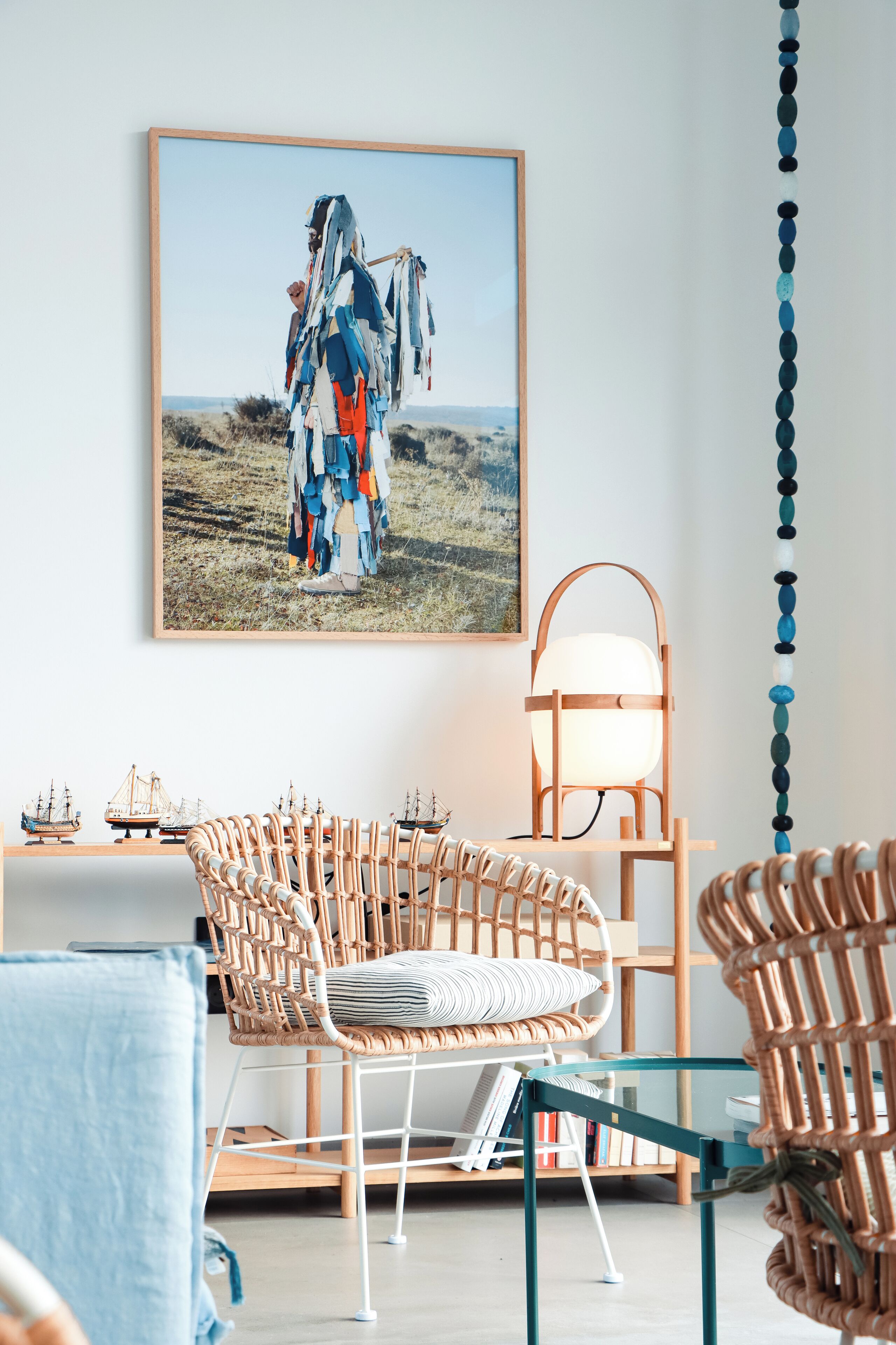 A room with wicker chairs, a glass table, and a framed picture on the wall.