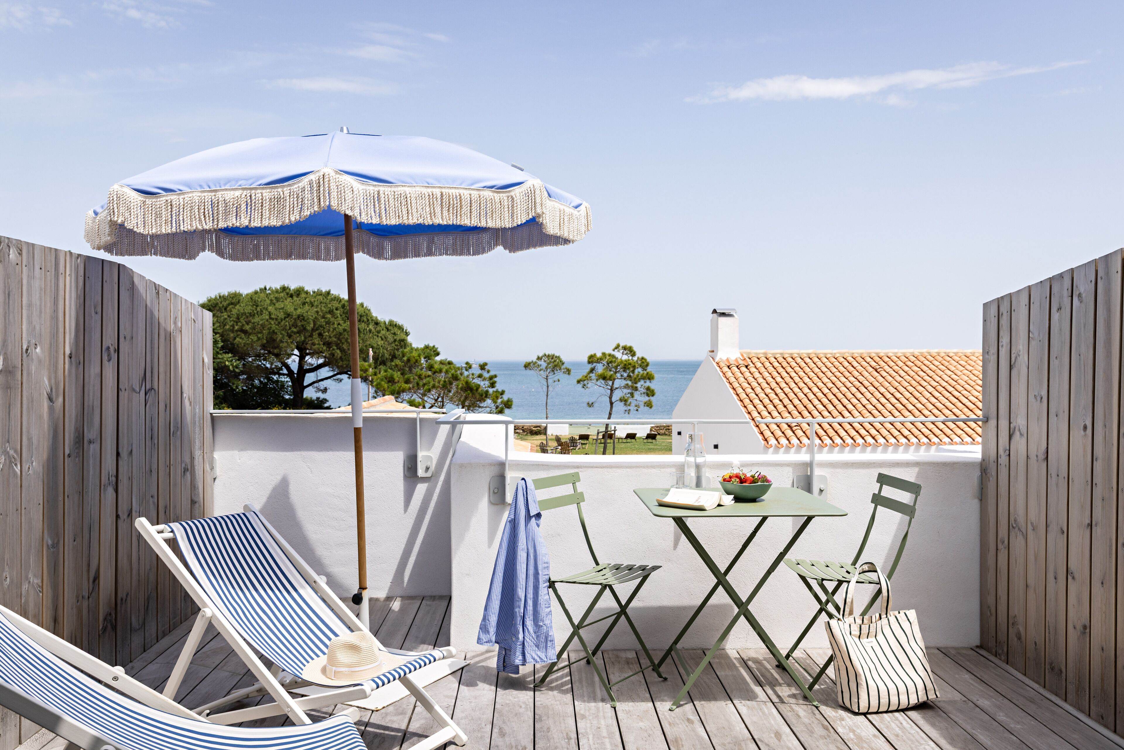 A wooden deck with a lounge chair, a table with chairs, and an umbrella.
