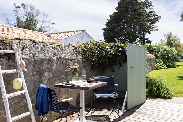 A wooden deck with a table, a chair, a ladder, and a green shed. - Les Hautes Mers - Fontenille Collection (Île d'Yeu)