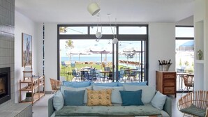Una sala de estar moderna con un ventanal grande, un sofá y un comedor con mobiliario de exterior.
