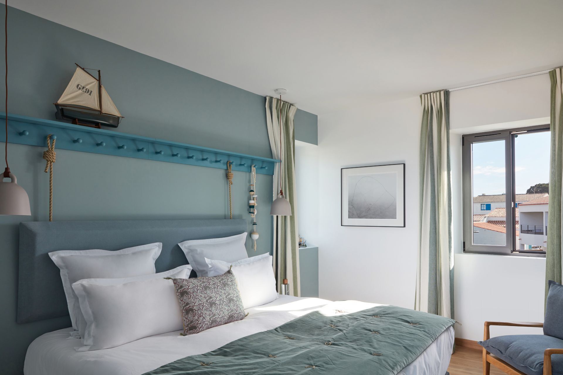 A bedroom with a bed, a headboard, a window, and a view of buildings outside.