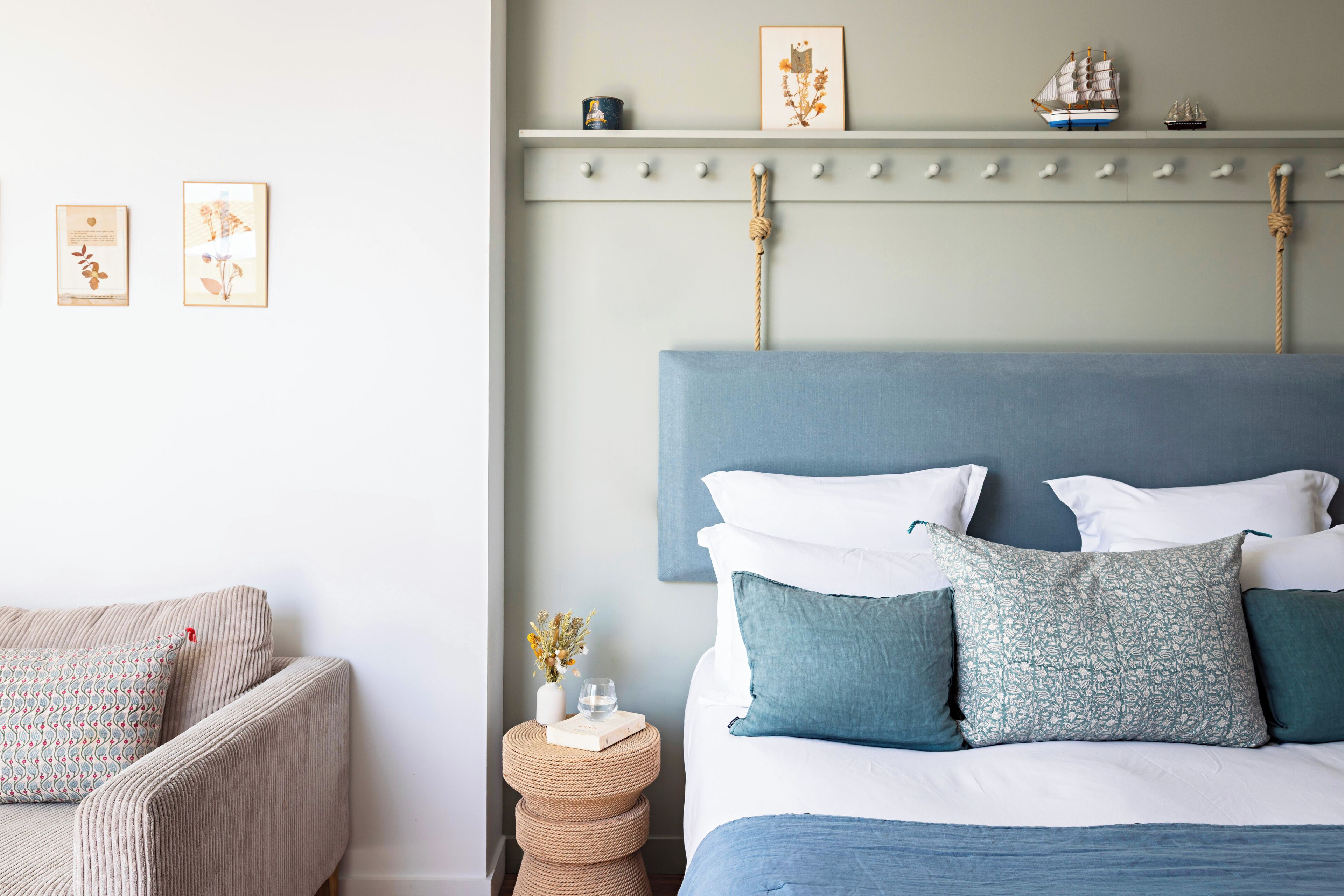 A bedroom with a bed, a chair, a bedside table, and wall decorations.