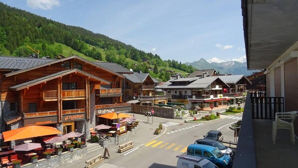 A mountain village with wooden buildings, outdoor seating, and a view of the mountains.