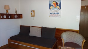 A room with a bed, a chair, a wall-mounted telephone, and a poster.