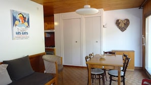 A dining area with a wooden table and chairs, a heart-shaped decoration on the wall, and a poster on the wall.