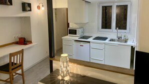 Eine kleine Küche mit Mikrowelle, Spüle und einem Fenster über der Arbeitsfläche.