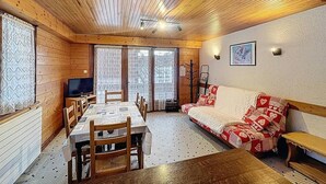 Een gezellig interieur van een chalet met een eettafel, stoelen, een bank en een televisie.