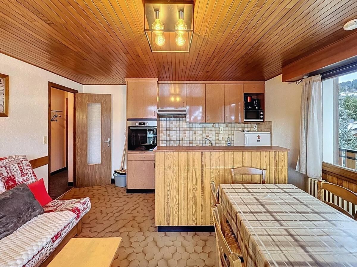 A compact room with a kitchenette, a sofa, a bed, and a window with a view.