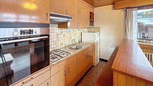 A compact kitchen with wooden cabinets, a built-in oven, a sink, and a refrigerator. - Wifi, 2nd floor, terrace, balcony, parking, 50m², Les Gets (Les Gets)