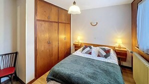 A bedroom with a bed, two bedside tables with lamps, a wardrobe, and a chair. - Wifi, 2nd floor, terrace, balcony, parking, 50m², Les Gets (Les Gets)