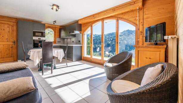 A modern kitchen with a dining area, large windows, and a TV. - Wifi, Ground floor, view mountain, terrace, parking, tv, 40m², Les Gets (Les Gets)